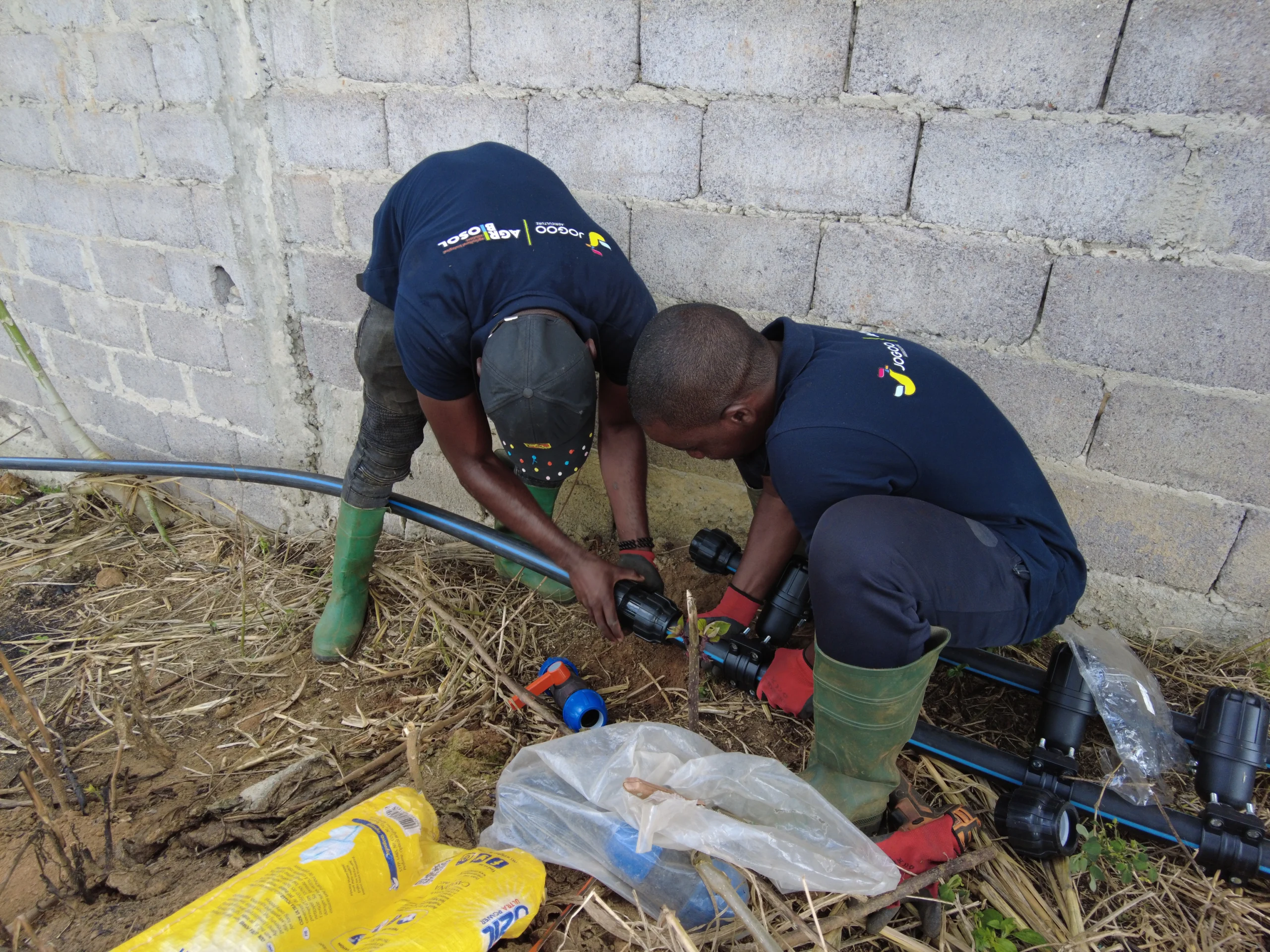 Deux techniciens JOGOO Agriculture raccordant un réseau d'irrigation sur un chantier